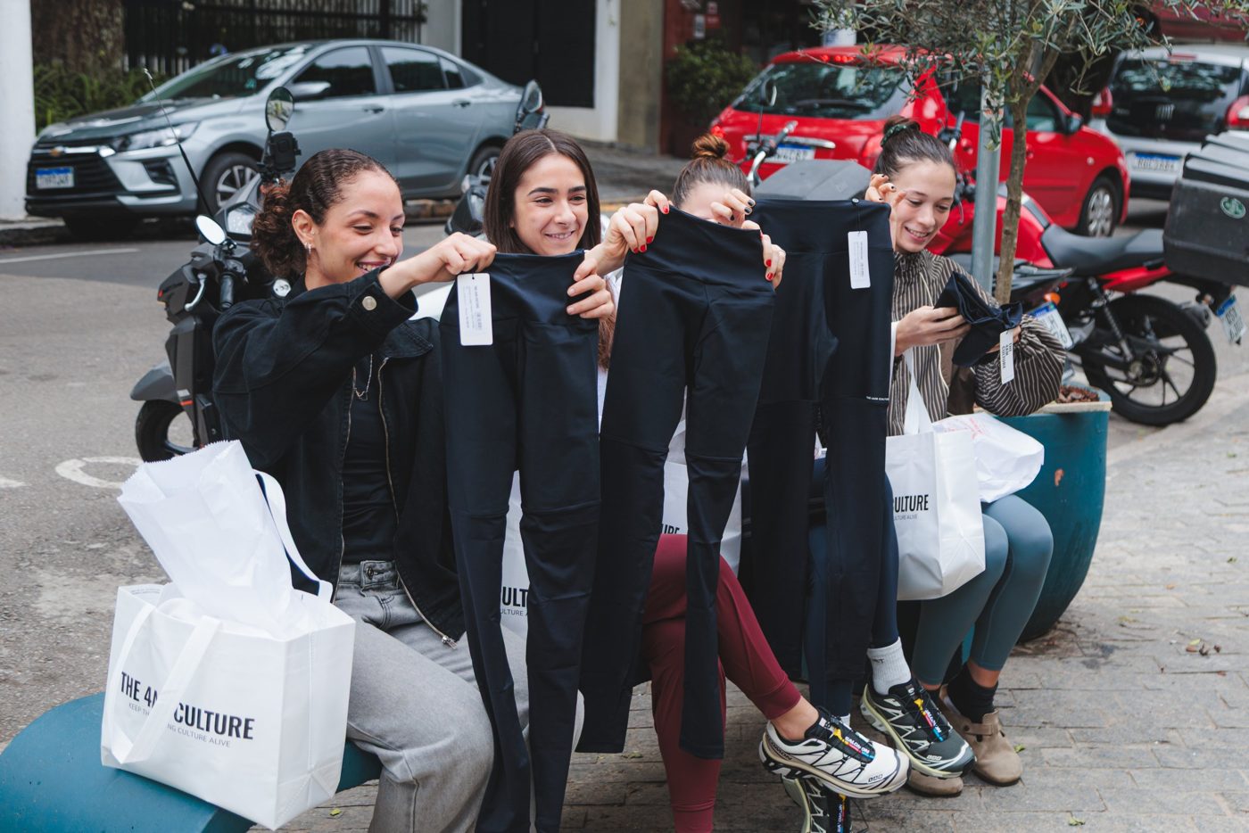 Clientes sentadas na frente da loja mostrando as leggings que ganharam de presente