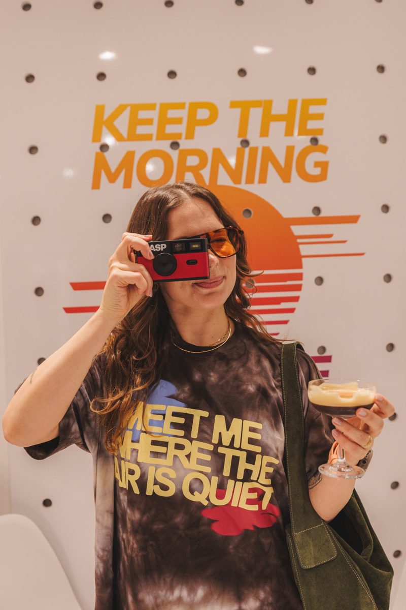 Cliente de camiseta tie-dye fotografando com câmera vermelha
