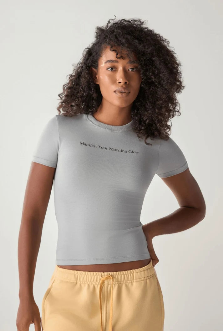 Baby tee cinza com a frase Manifest Your Morning Glow